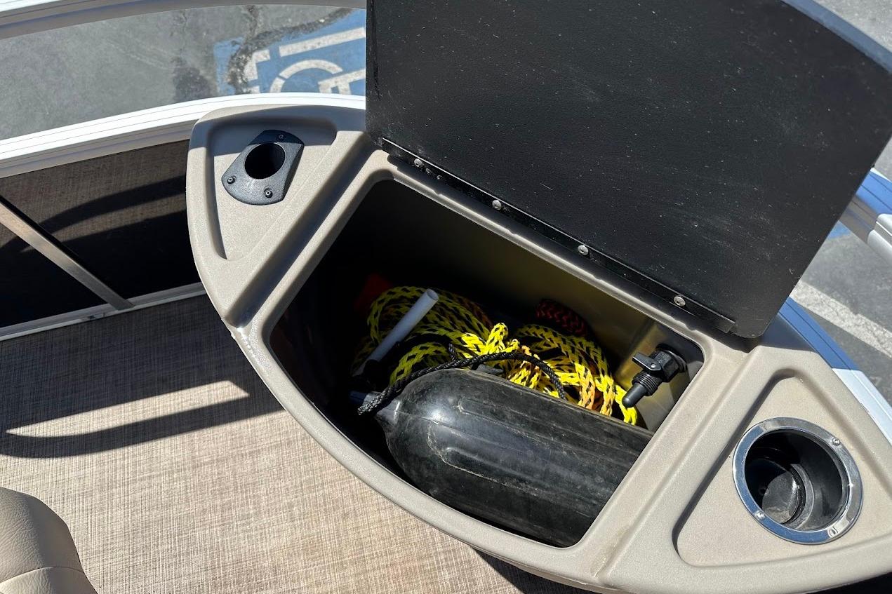 Storage compartment on 2022 Sun Tracker Bass Buggy 18 DLX pontoon boat with cup holders.