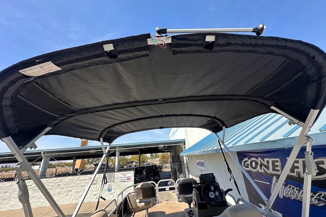 2022 Sun Tracker Bass Buggy 18 DLX with bimini top, docked under clear blue sky.