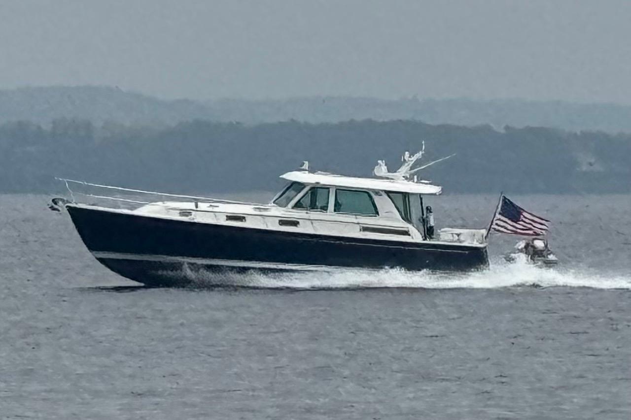 2025 Sabre 48 Salon Express yacht cruising on open water with American flag.