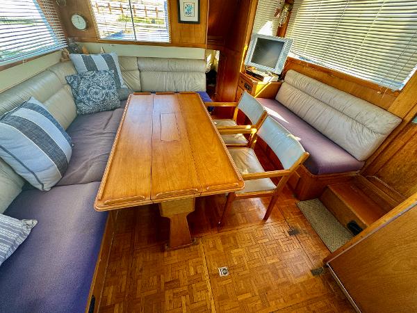 1979 Grand Banks Classic yacht interior with wooden table, cushioned seating, and a small TV.