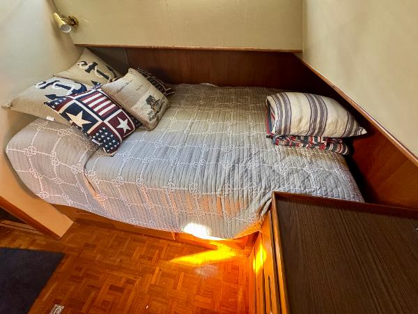 Cozy cabin bed in 1979 Grand Banks Classic boat with nautical-themed pillows.