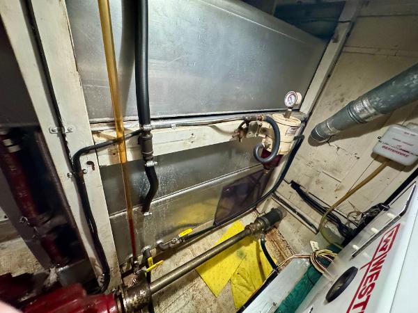 Engine room of 1979 Grand Banks Classic boat with visible pipes and machinery.