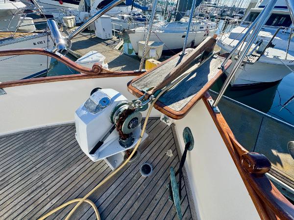 1979 Grand Banks Classic yacht deck with anchor winch and wooden railings in marina.