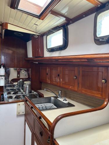 1975 Salar 40 yacht kitchen with wooden cabinets and stainless steel sink.