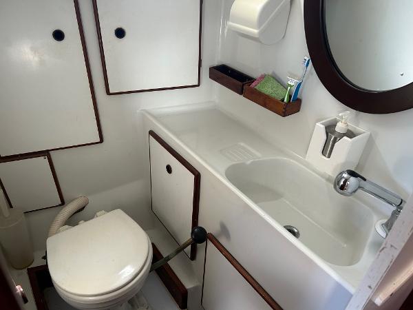1975 Salar 40 yacht bathroom with sink, toilet, mirror, and storage cabinets.