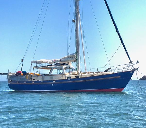 1975 Salar 40 sailboat with blue hull anchored on calm water.