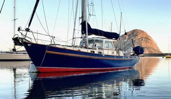 Salar 40 sailboat from 1975 on calm water with mountain backdrop.