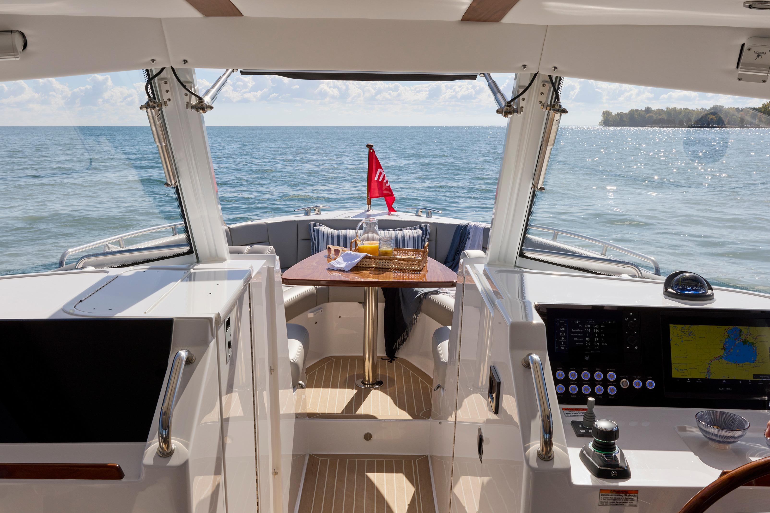 Luxurious MJM 38x yacht interior with ocean view, featuring a dining area and navigation controls.