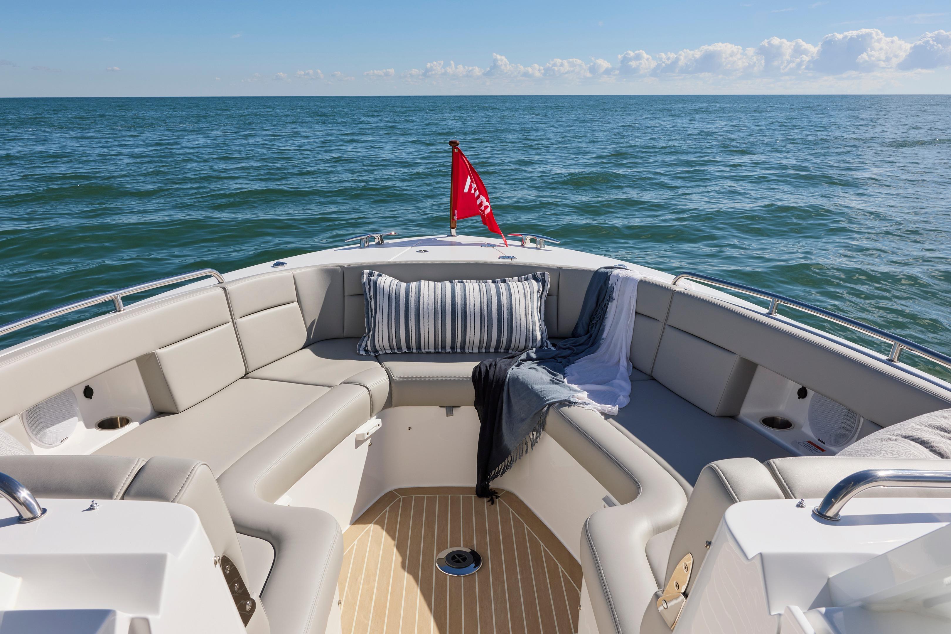 Luxurious seating on 2026 MJM 38x boat, ocean view, striped pillow, and red flag.