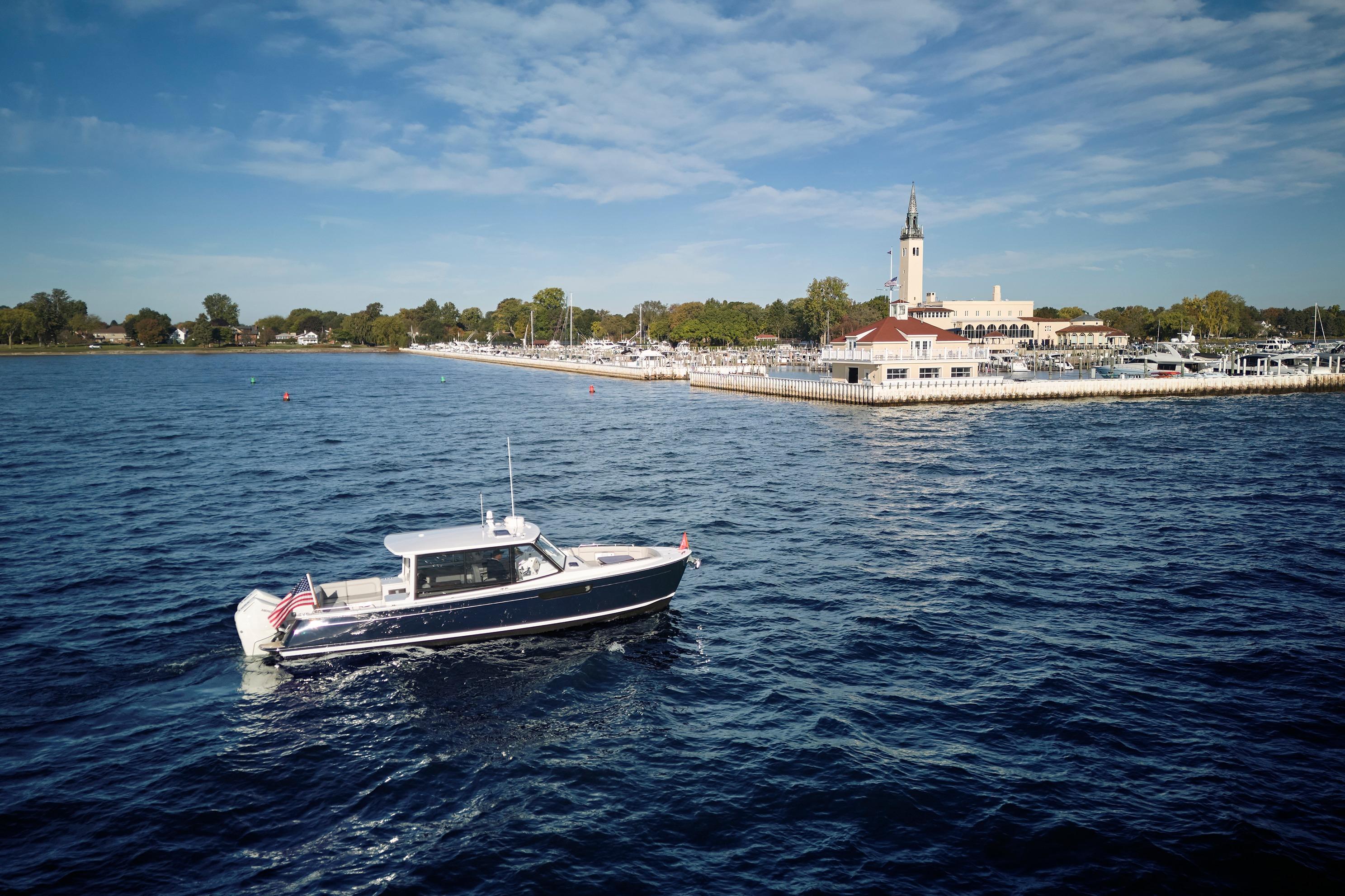 MJM 38x boat cruising near a marina with a clock tower, 2026 model.