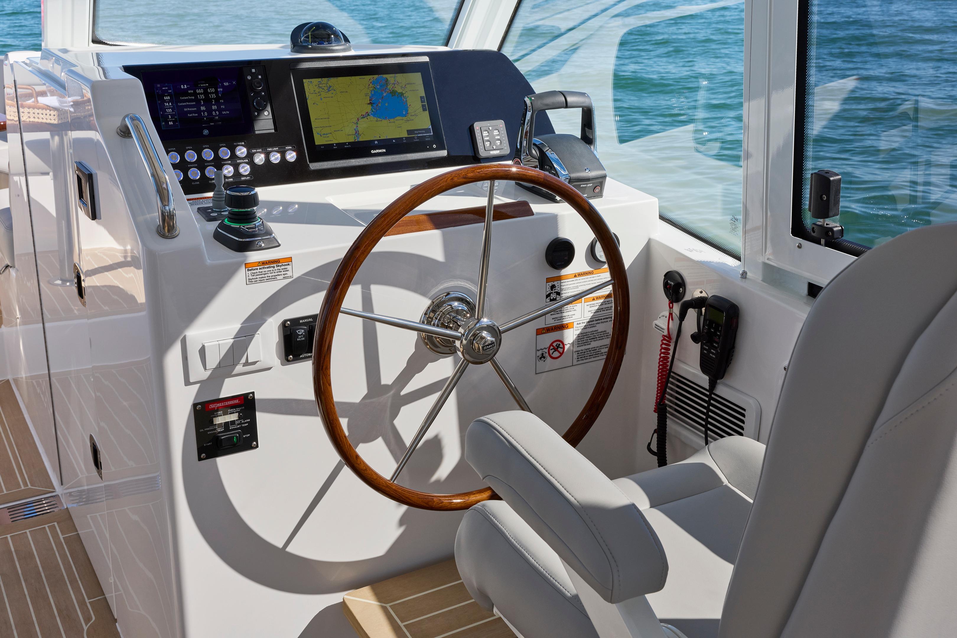 Helm of 2026 MJM 38x boat with modern navigation controls and wooden steering wheel.