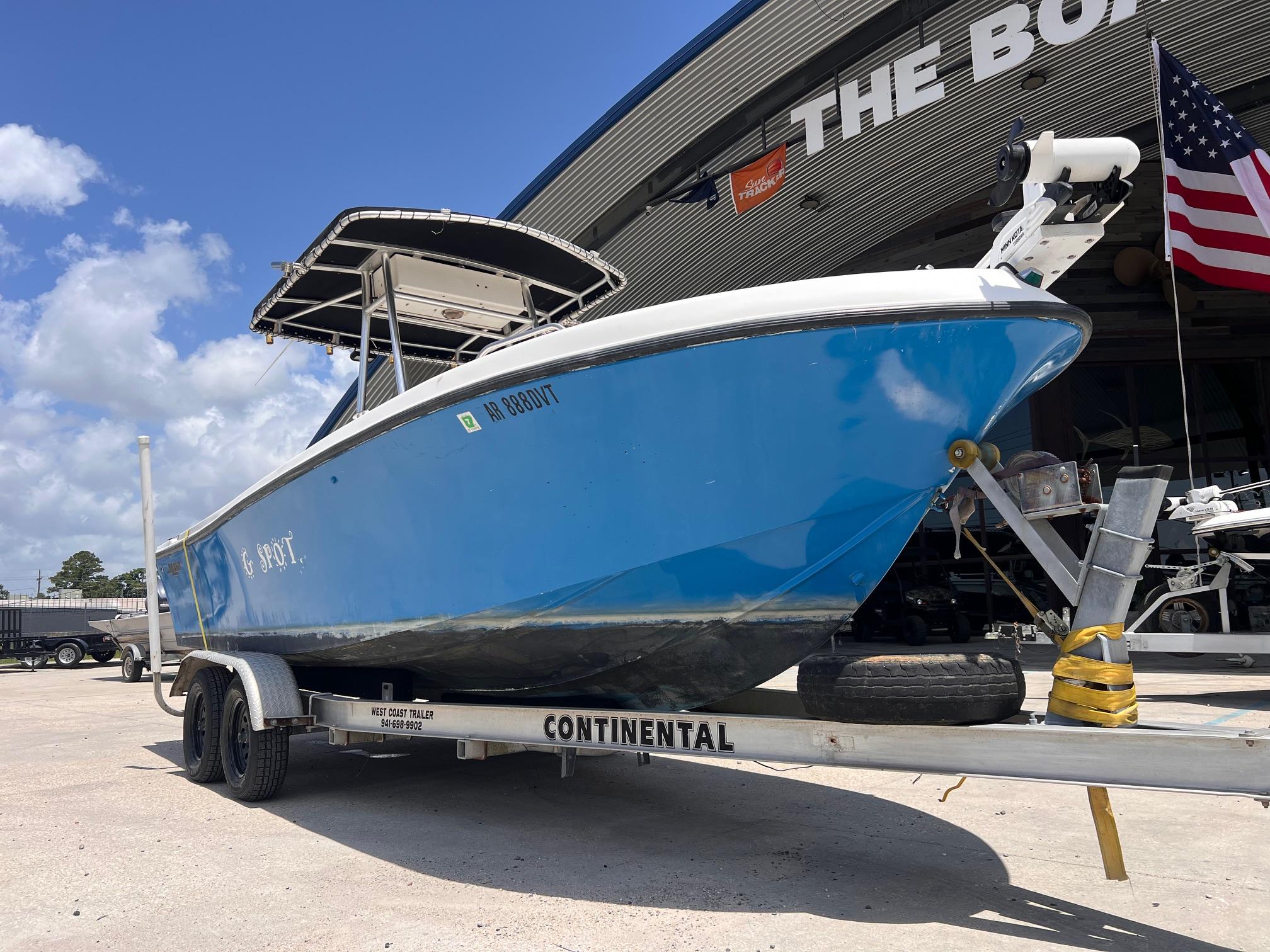 1998 Mako 221 CC boat on trailer, parked outside with American flag and blue sky.