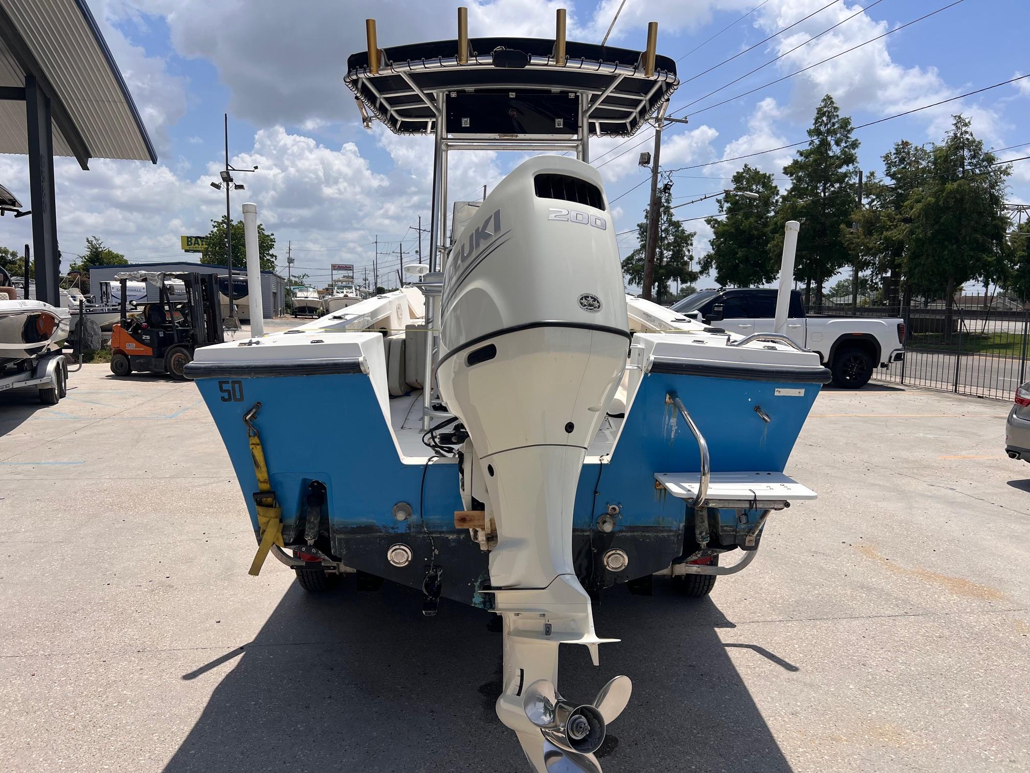 1998 Mako 221 CC boat with Suzuki outboard motor, parked outdoors under a cloudy sky.