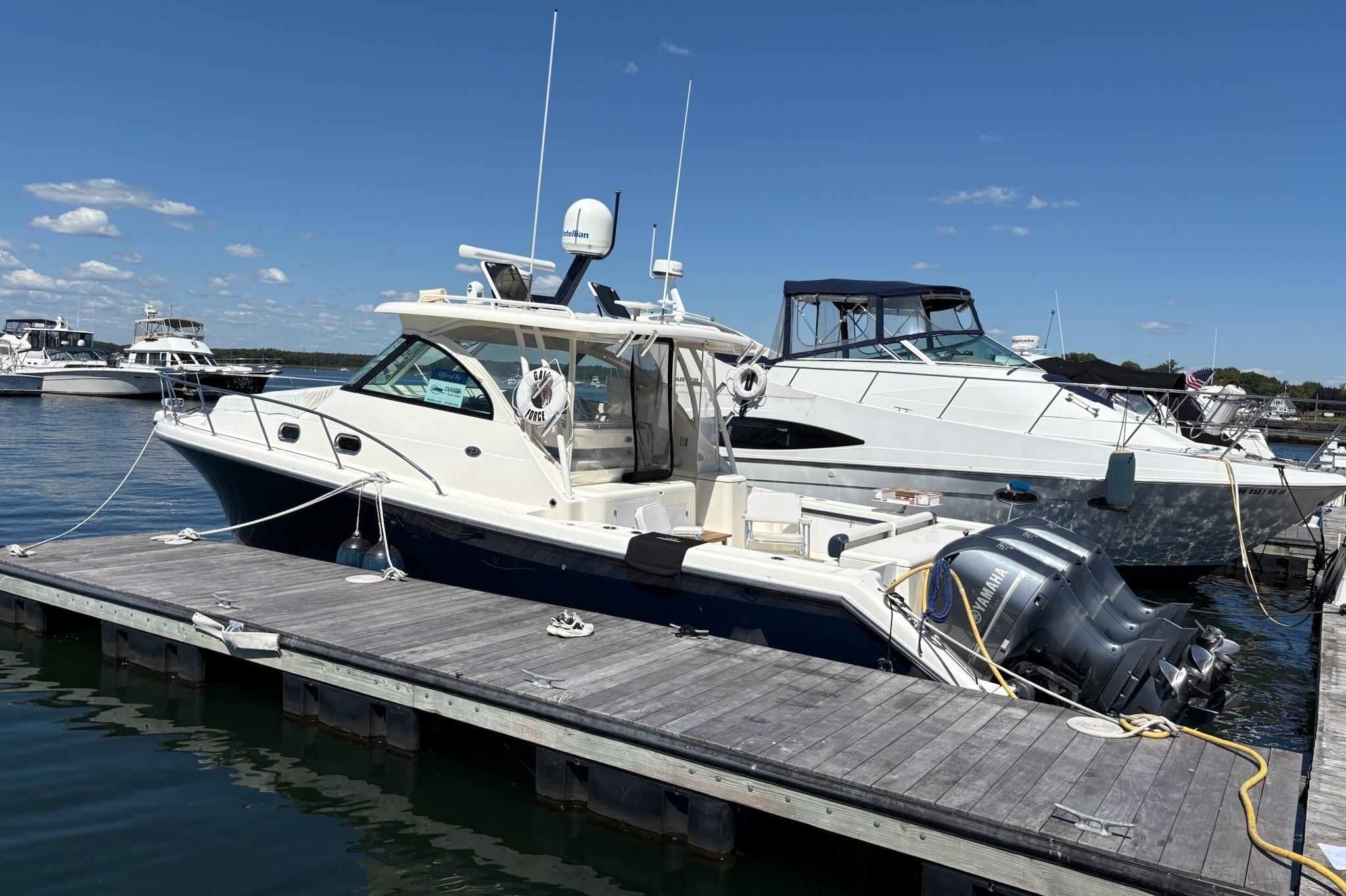 2009 Pursuit OS 375 Offshore boat docked at marina under clear blue sky.
