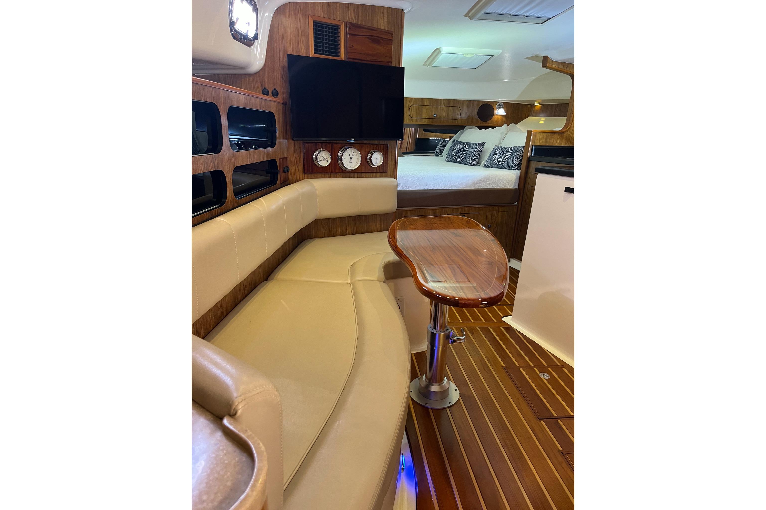 Luxurious interior of 2009 Pursuit OS 375 Offshore boat with wood accents and cozy seating.