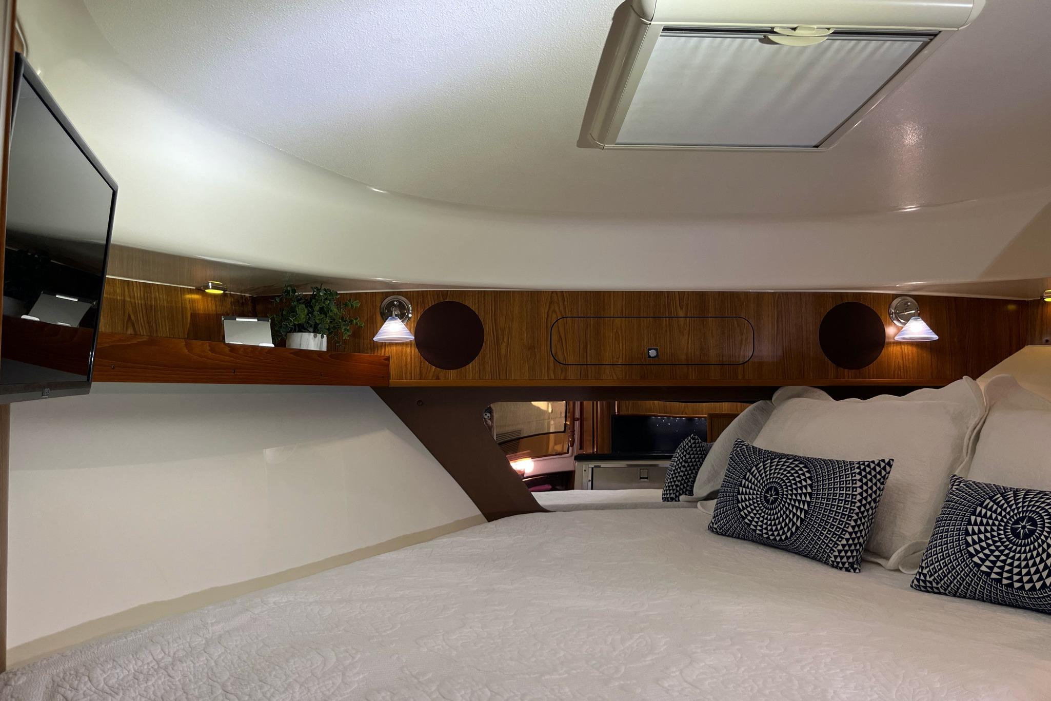 Luxurious cabin interior of 2009 Pursuit OS 375 Offshore with cozy bedding and modern lighting.