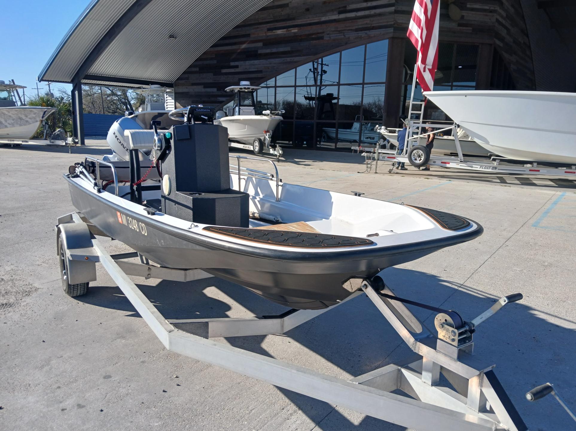 1980 Boston Whaler 15 Montauk boat on trailer, parked outside a modern building.