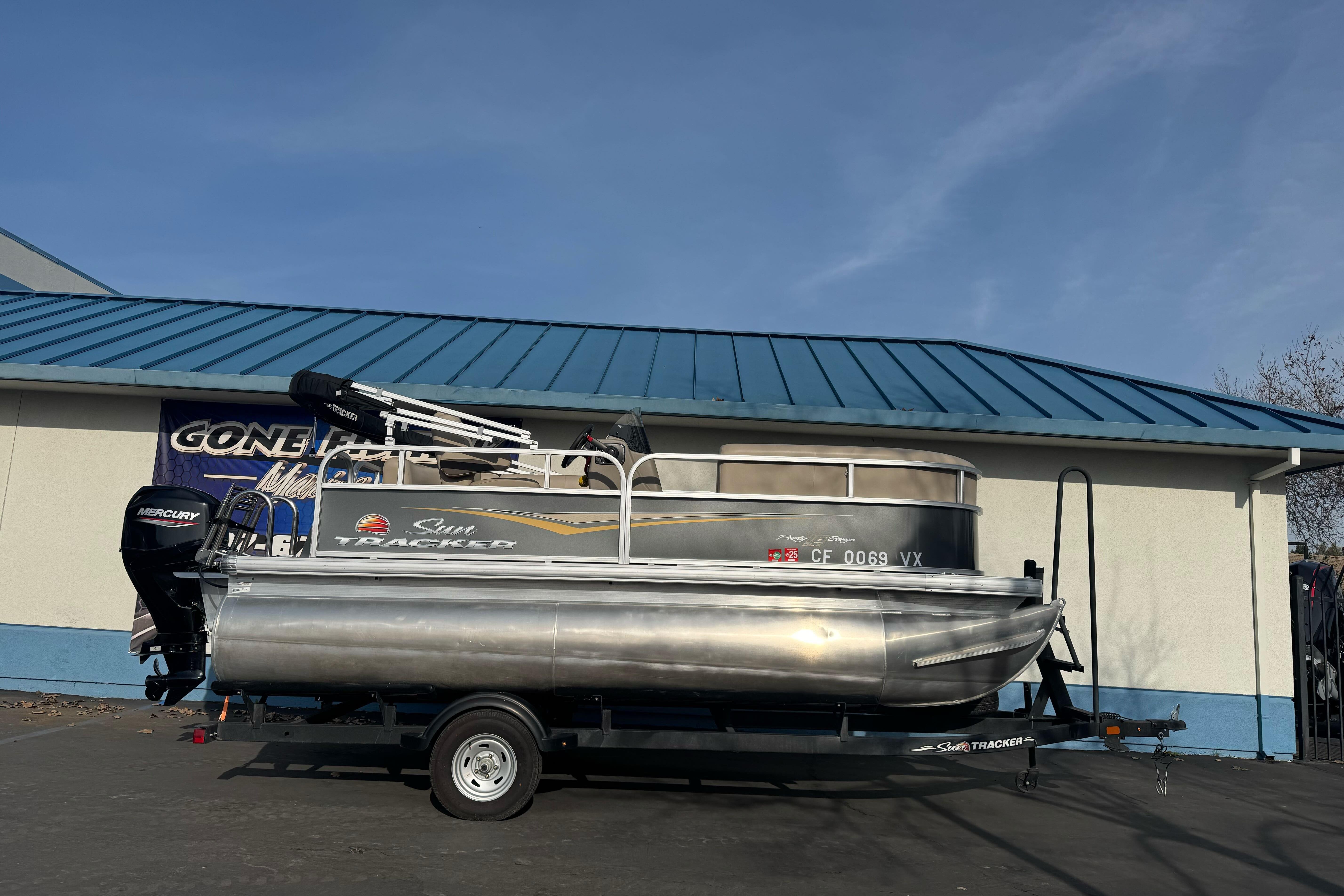 2024 Sun Tracker Party Barge 16 DLX pontoon boat on trailer, parked outdoors.