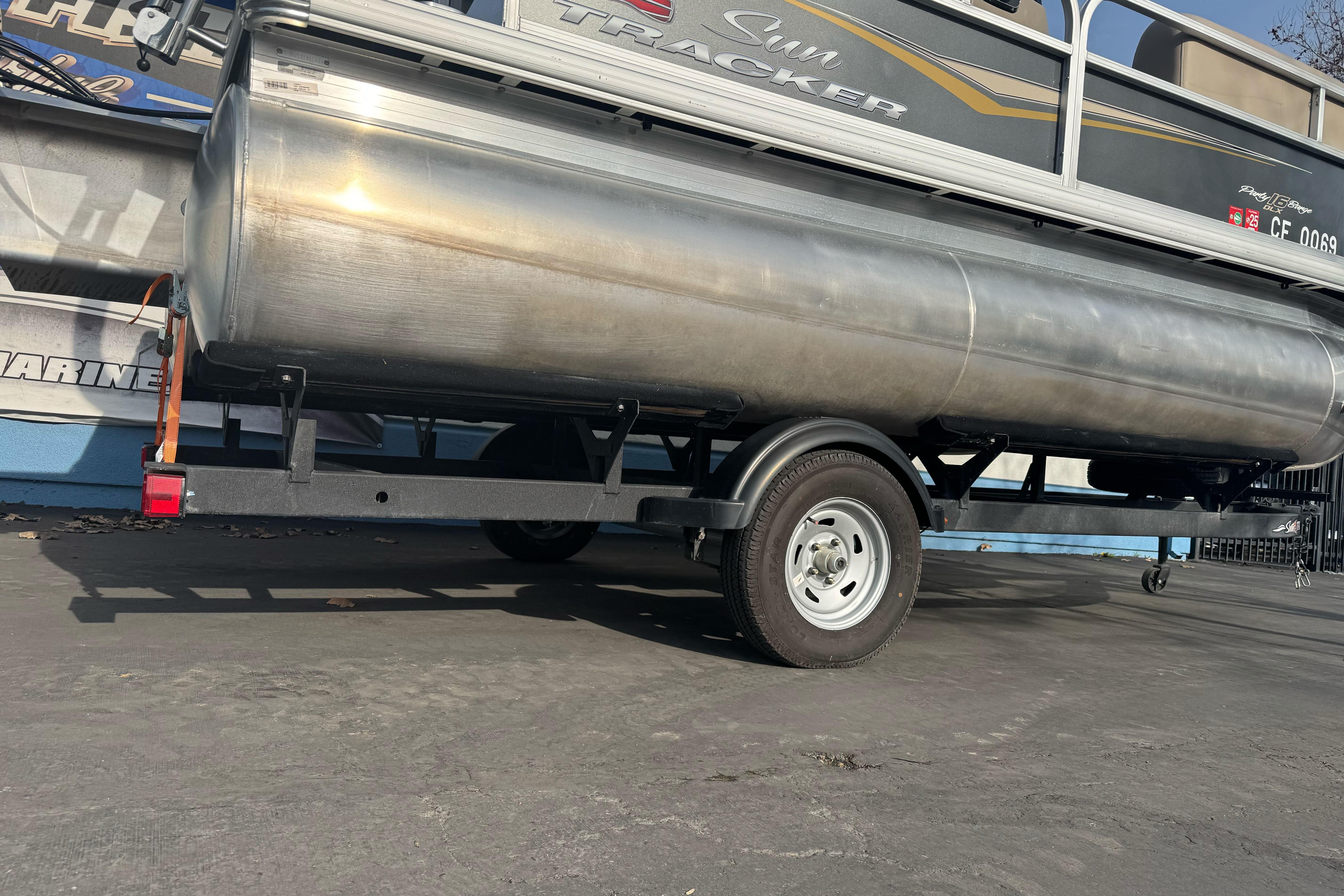 2024 Sun Tracker Party Barge 16 DLX pontoon boat on trailer, side view.