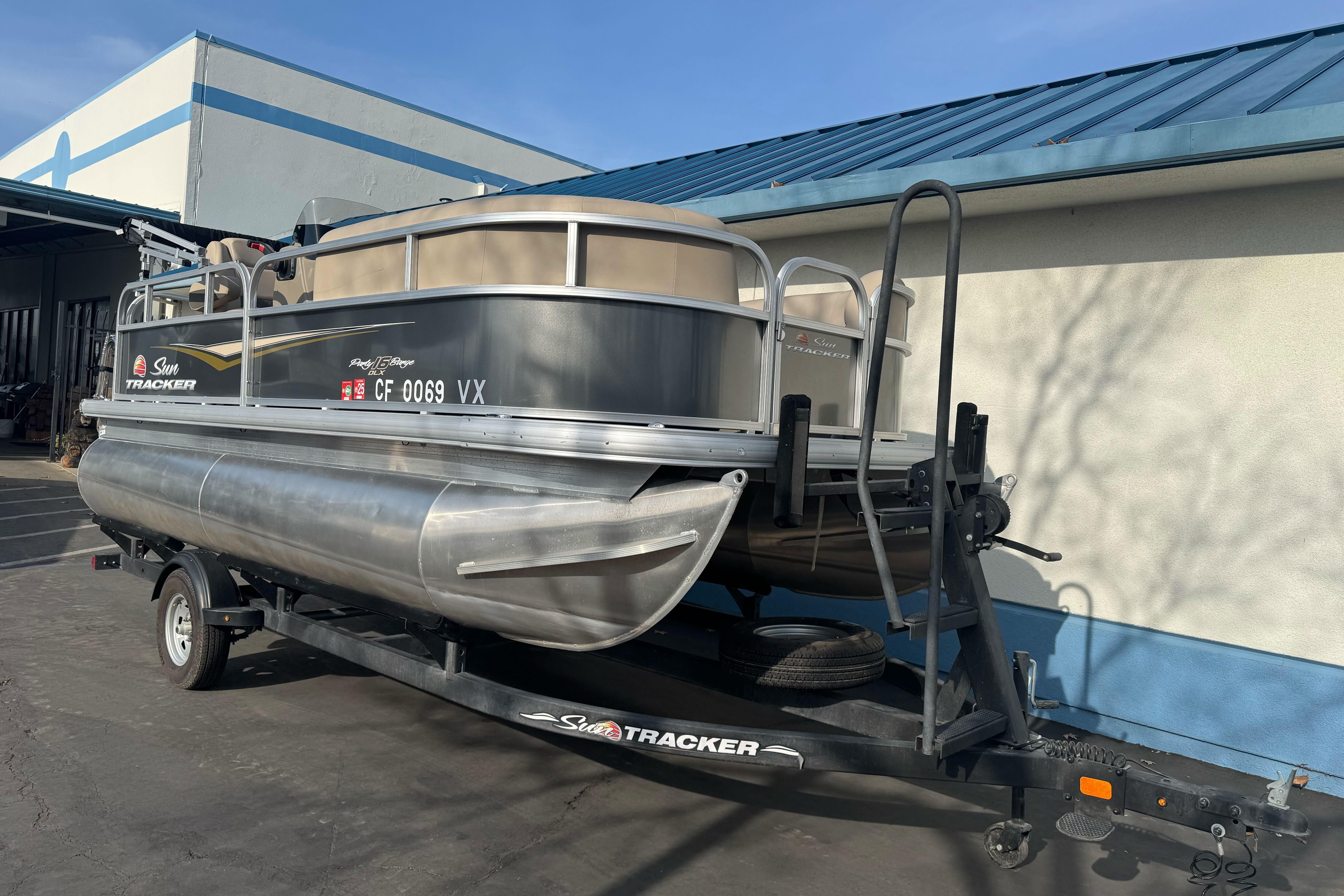2024 Sun Tracker Party Barge 16 DLX pontoon boat on trailer, parked outdoors.