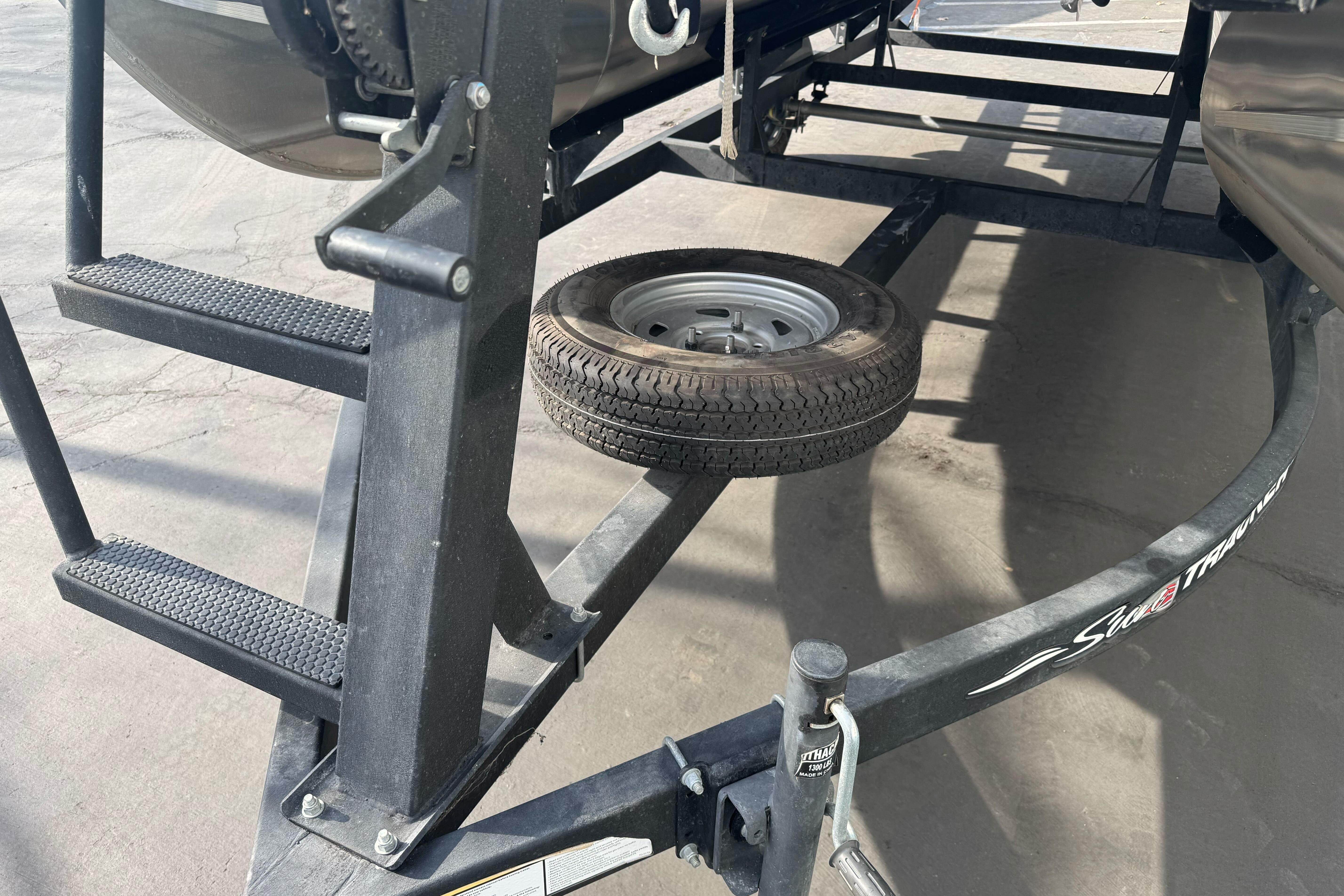 Trailer of 2024 Sun Tracker Party Barge 16 DLX with spare tire and ladder.