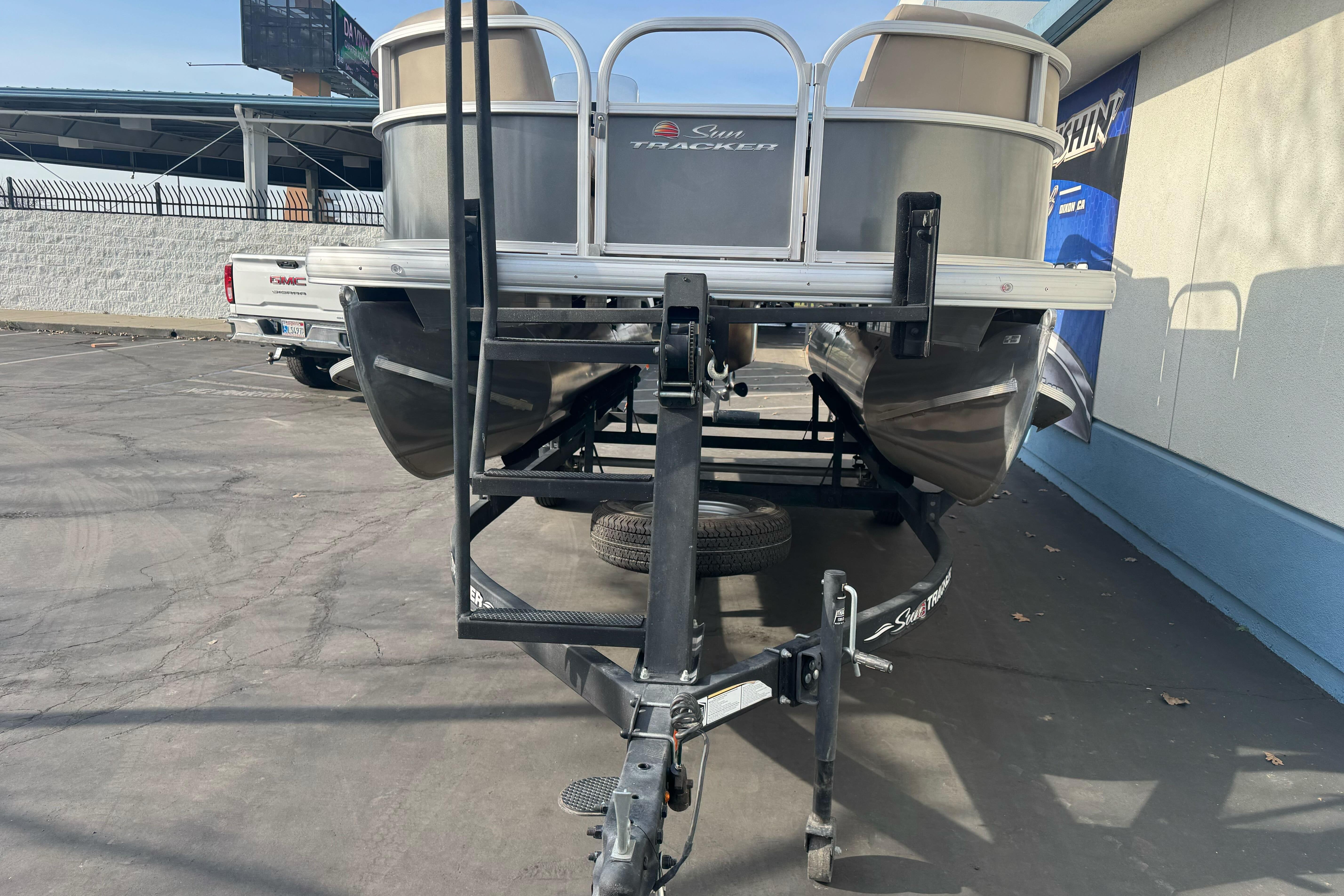 2024 Sun Tracker Party Barge 16 DLX pontoon boat on trailer in parking lot.