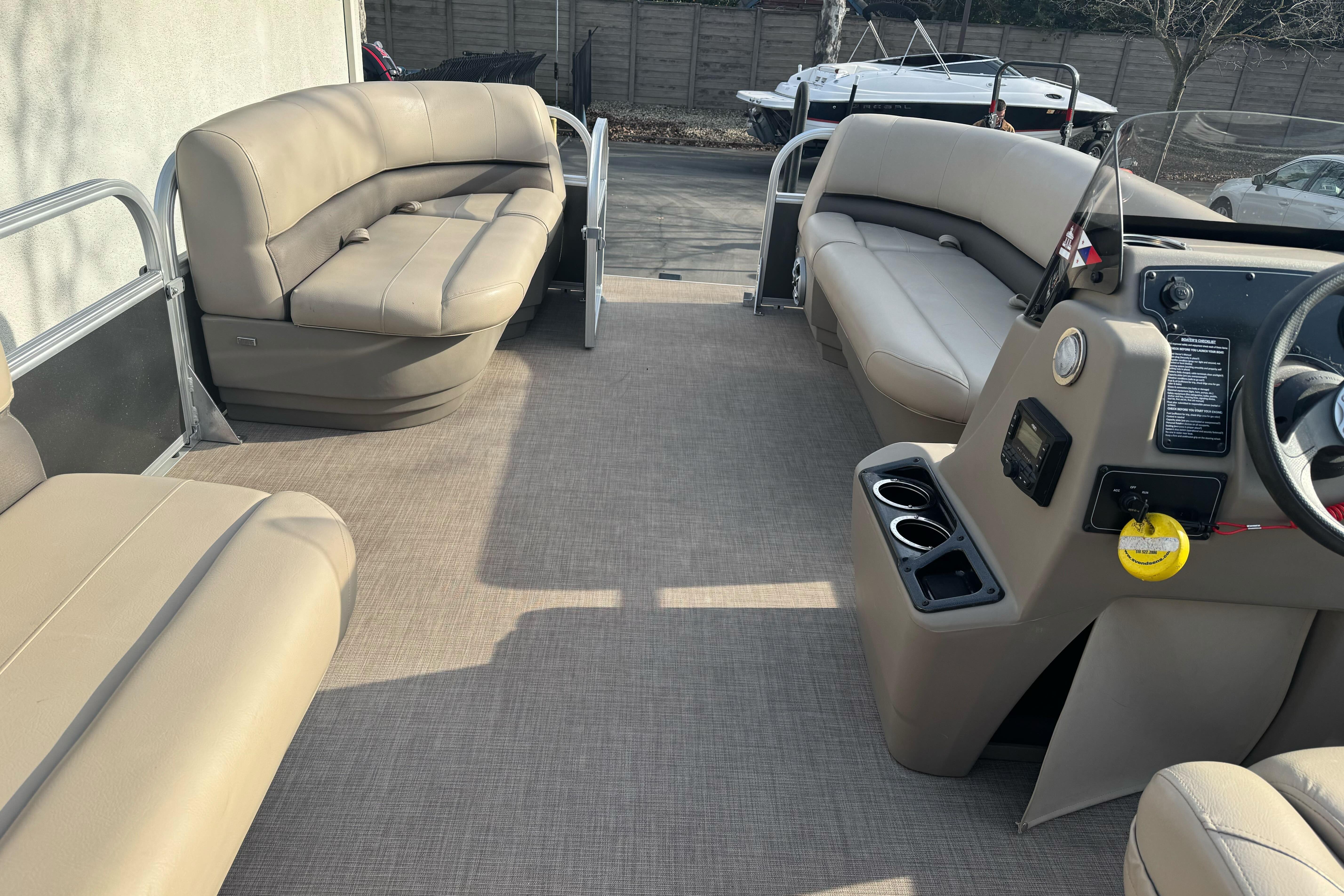 2024 Sun Tracker Party Barge 16 DLX interior with beige seating and steering console.