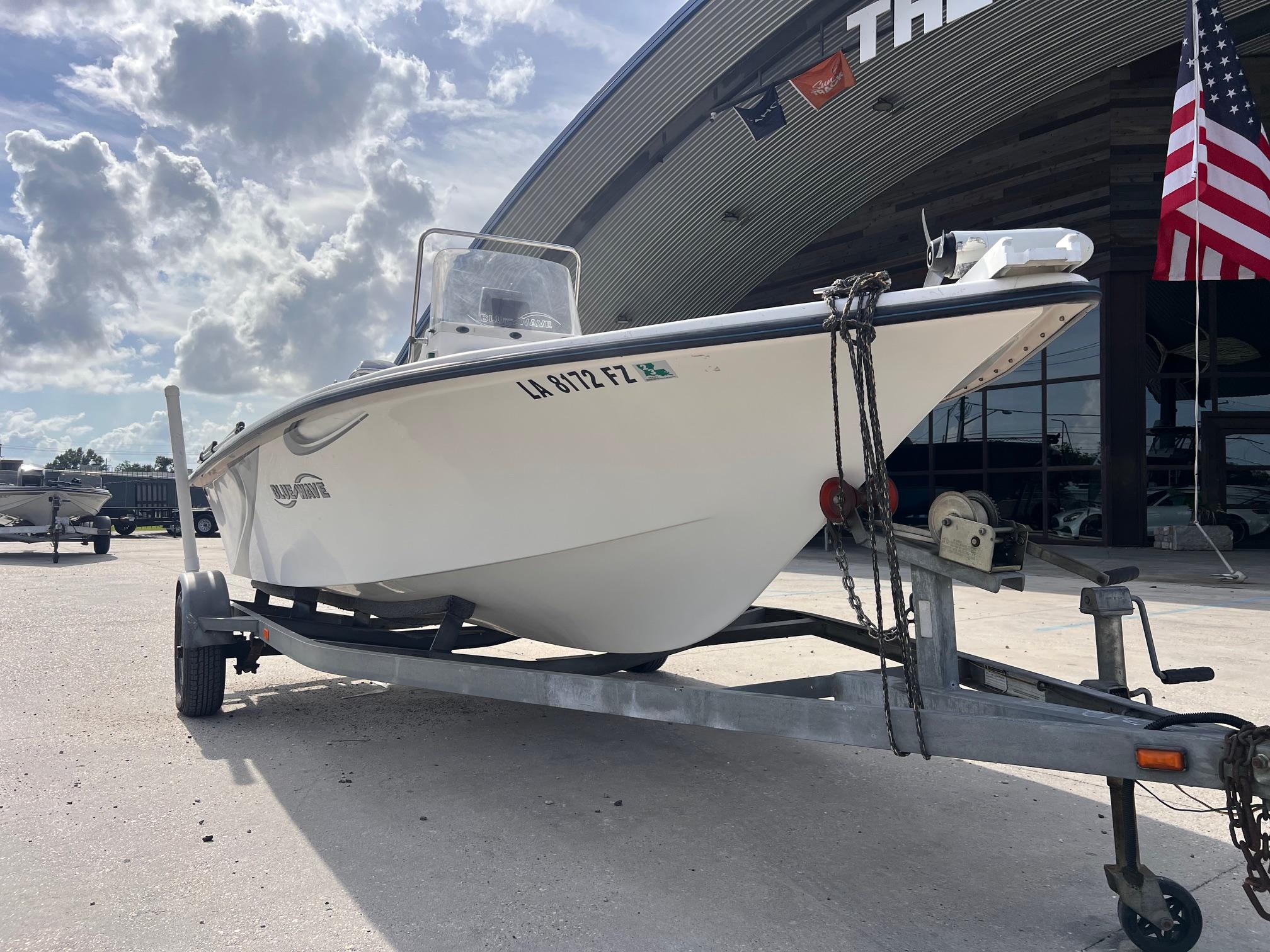 2010 Blue Wave 160 V Bay boat on trailer, parked outside dealership under cloudy sky.