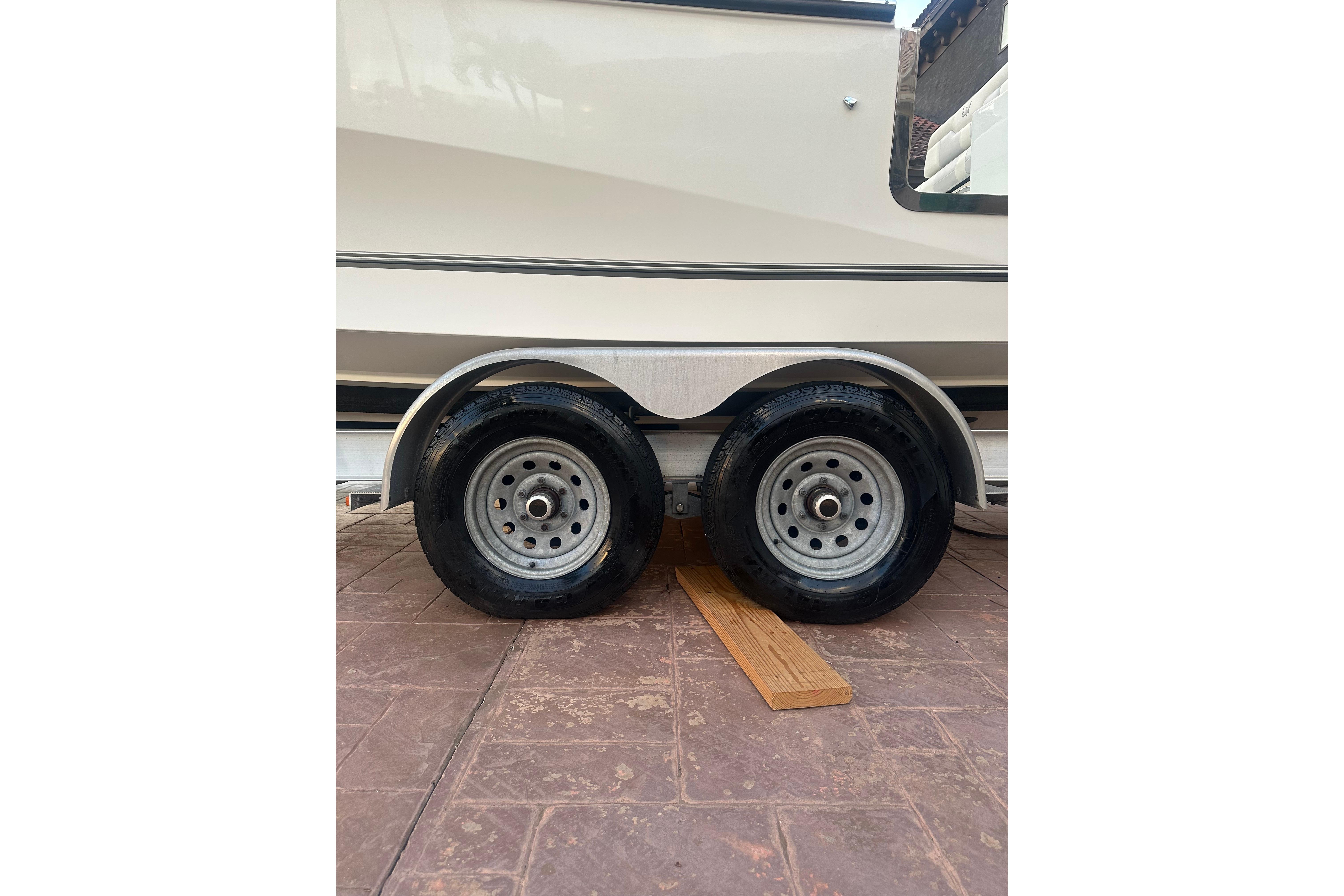Trailer wheels of a 2020 Mako 235 boat on a paved surface.