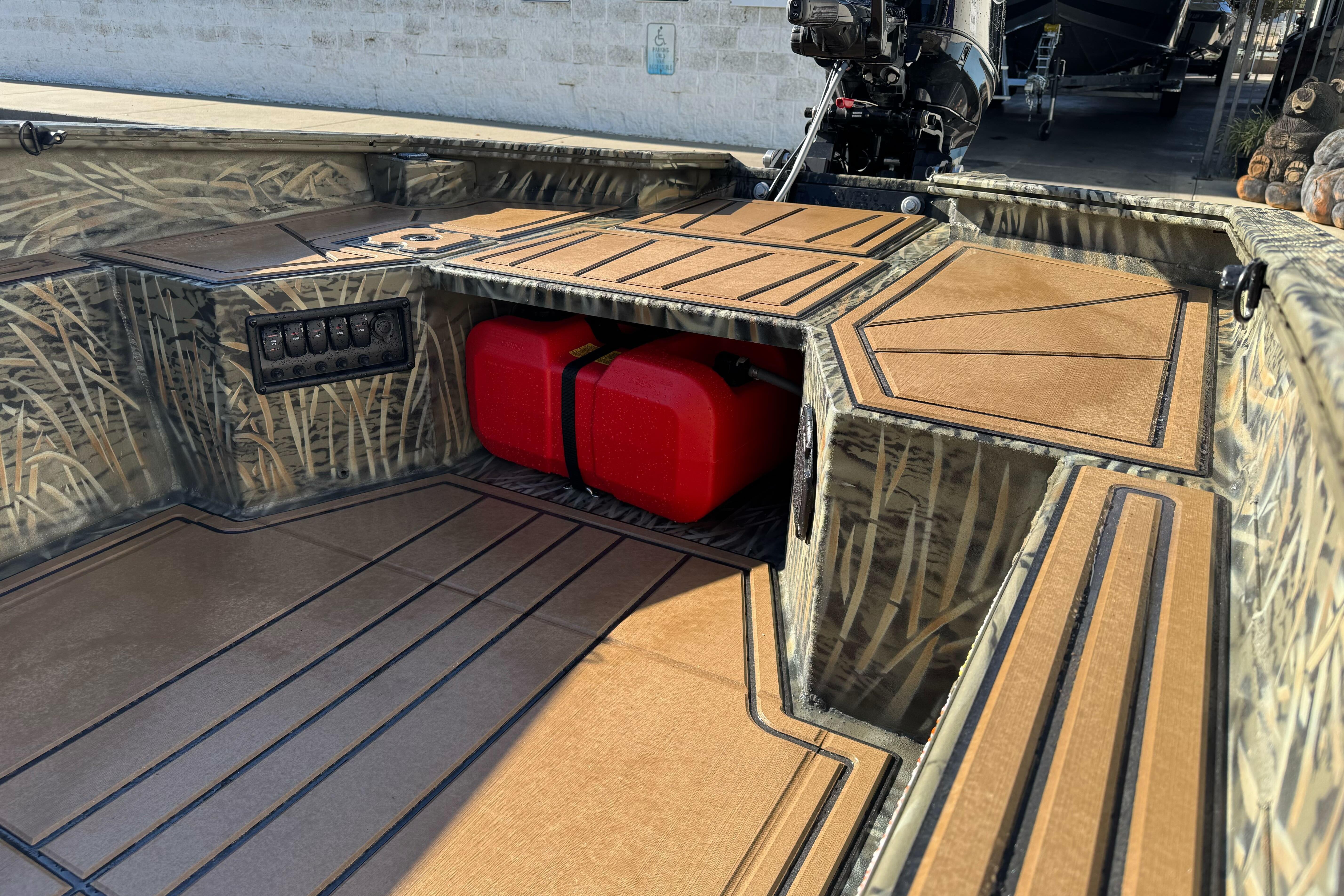 2026 Tracker Grizzly 1650 T Prairie Wings Edition boat interior with camouflage design and red fuel tanks.