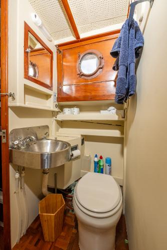 1939 Stephens Brothers Bridgedeck Cruiser bathroom with porthole, sink, and toilet.