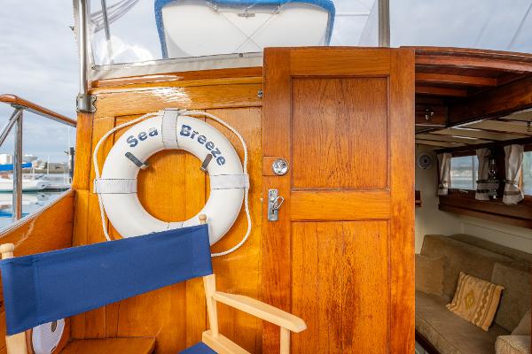 1939 Stephens Brothers Bridgedeck Cruiser with wooden door, life preserver, and blue chair.