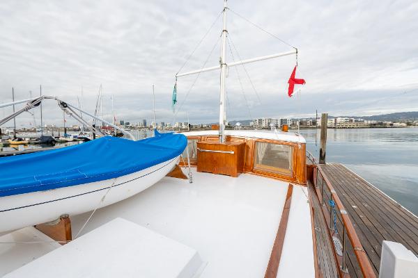 1939 Stephens Brothers Bridgedeck Cruiser docked, featuring a blue-covered boat on deck.