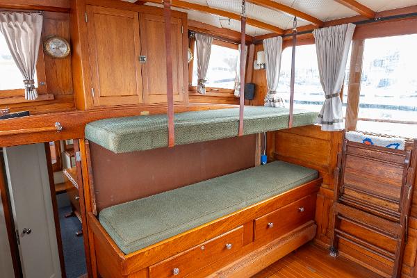 1939 Stephens Brothers Bridgedeck Cruiser interior with wooden bunk beds and storage.