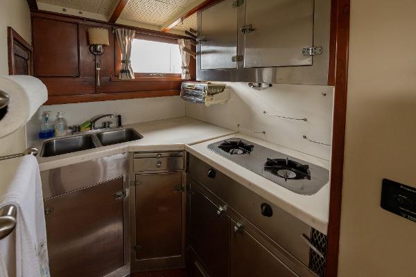 1939 Stephens Brothers Bridgedeck Cruiser kitchen with stainless steel appliances and wooden cabinetry.