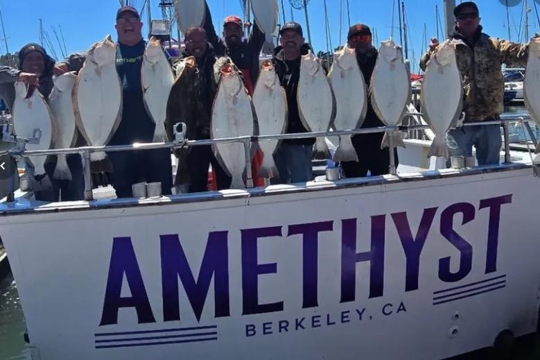 Group holding fish on 1978 Uniflite 50 boat "Amethyst" in Berkeley, CA marina.