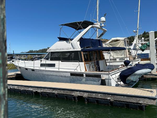 1987 Bayliner 3888 Motoryacht docked at marina under clear blue sky.