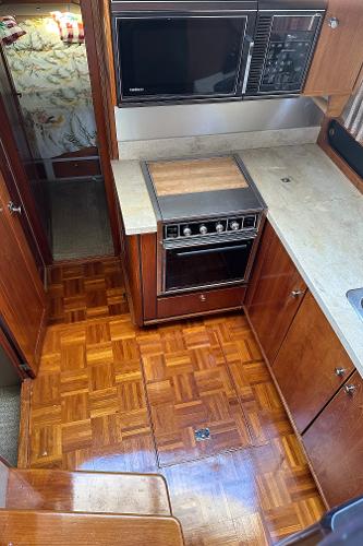 1987 Bayliner 3888 Motoryacht kitchen with wood flooring, stove, and microwave.