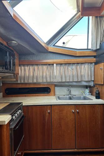 1987 Bayliner 3888 Motoryacht kitchen with wood cabinets, stove, and sink under skylight.