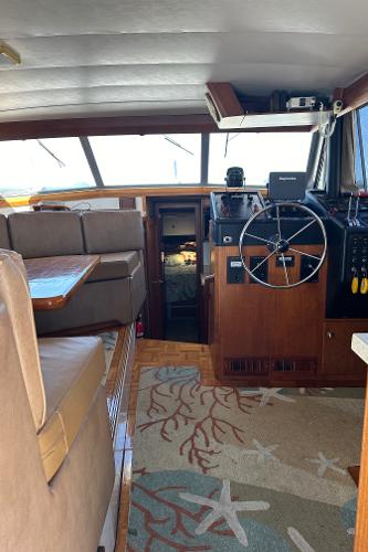 Interior of 1987 Bayliner 3888 Motoryacht with helm, seating, and nautical-themed carpet.