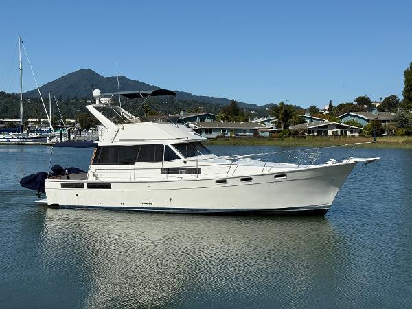 1987 Bayliner 3888 Motoryacht cruising on calm waters with scenic background.