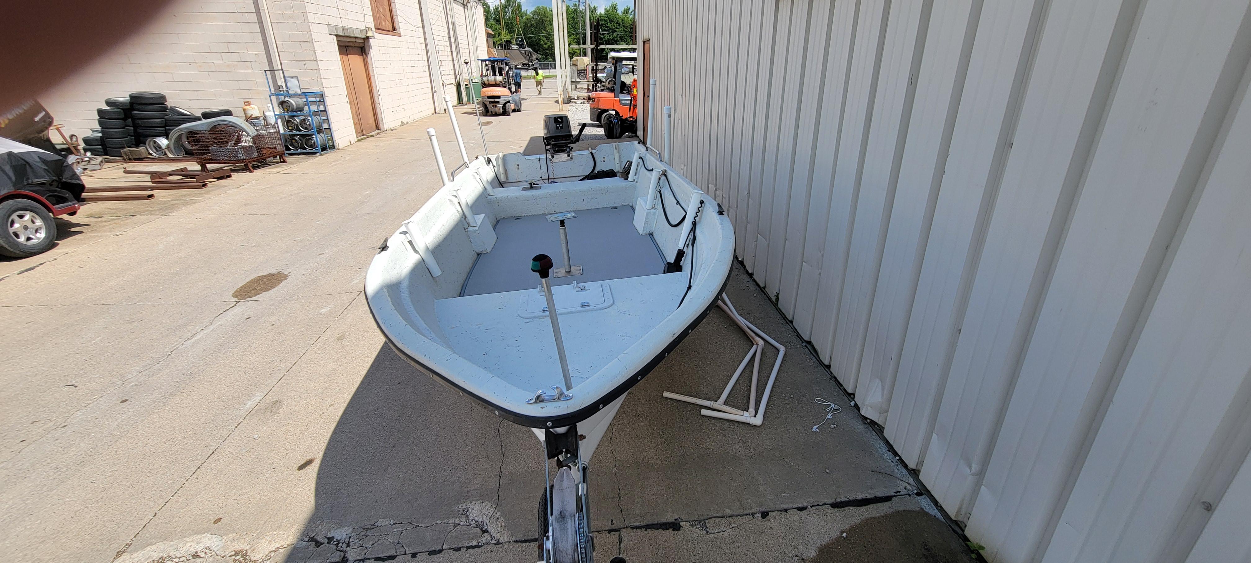 1996 Tracker Pro Angler V 16 boat parked beside a building on a sunny day.