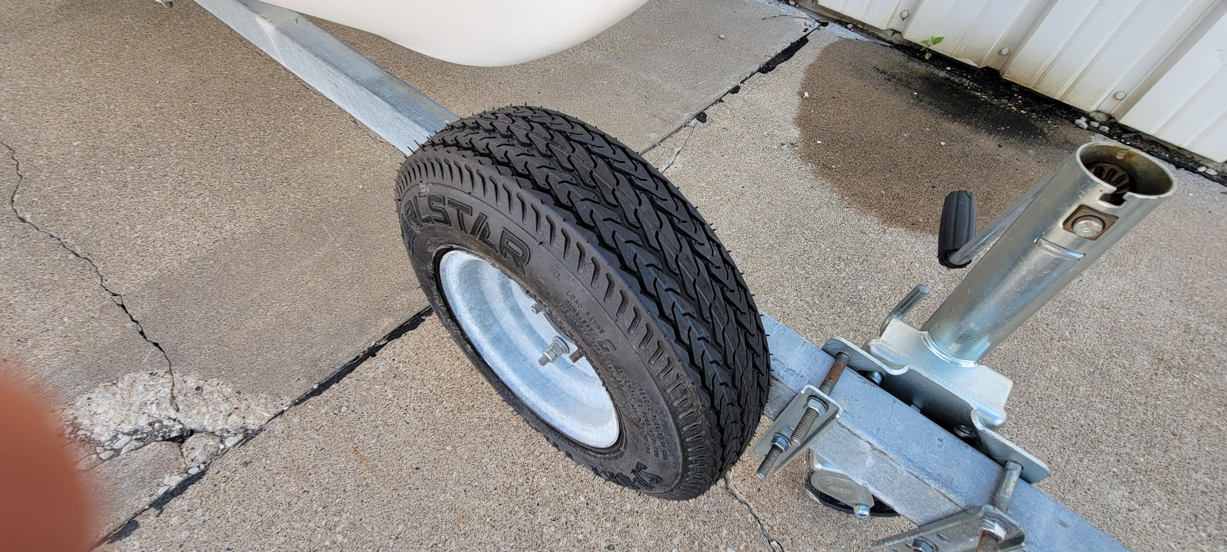Trailer wheel of a 1996 Tracker Pro Angler V 16 on concrete surface.