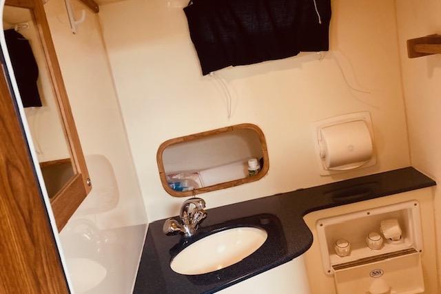 2015 Eastern 270 Islander boat bathroom with sink, mirror, and storage.