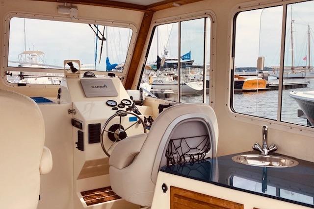 Interior of 2015 Eastern 270 Islander boat with helm, seating, and marina view.
