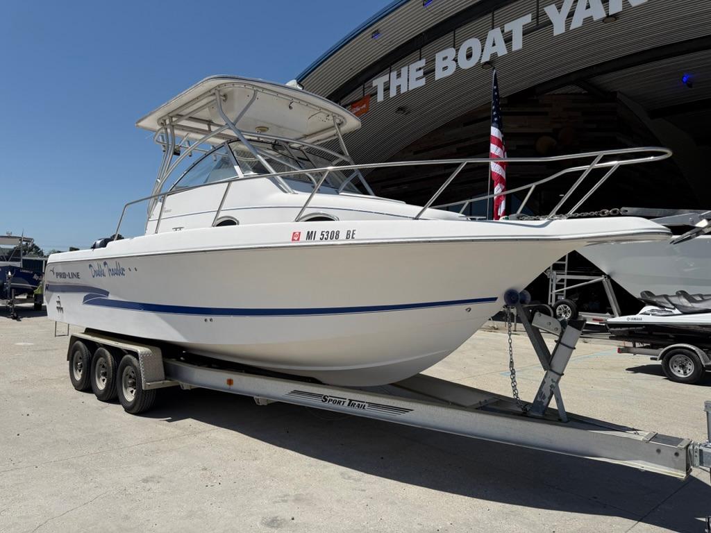 2000 Pro-Line 27 Walk boat on trailer outside a yacht facility.