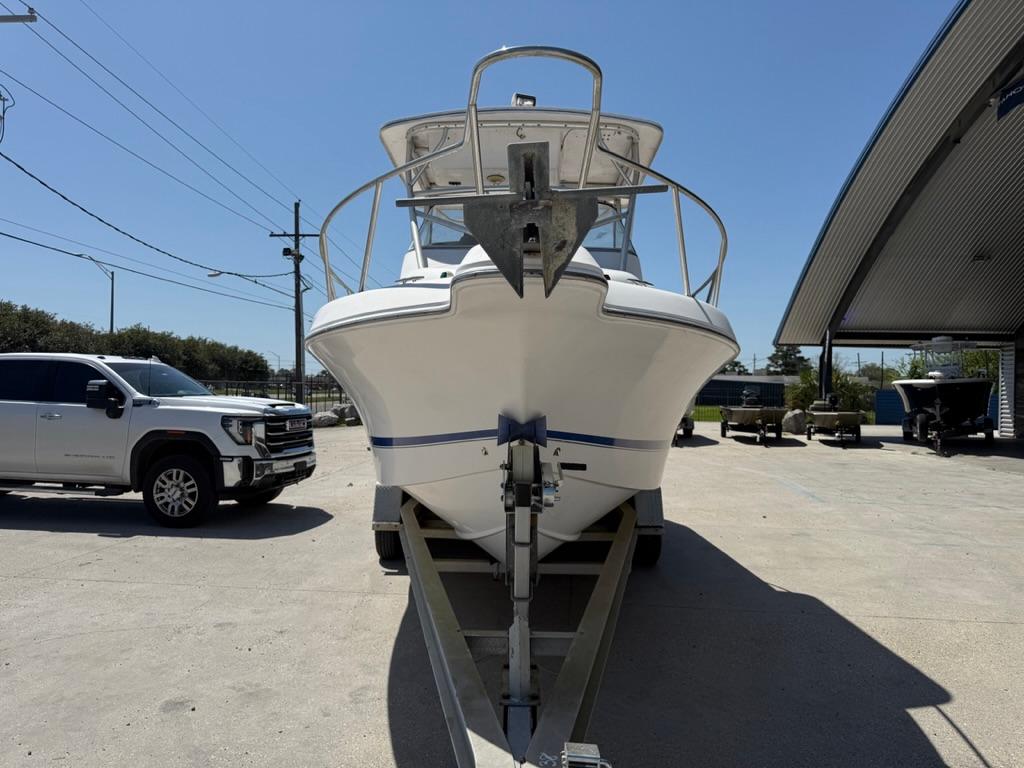 2000 Pro-Line 27 Walk boat on trailer, parked outdoors near a truck and building.
