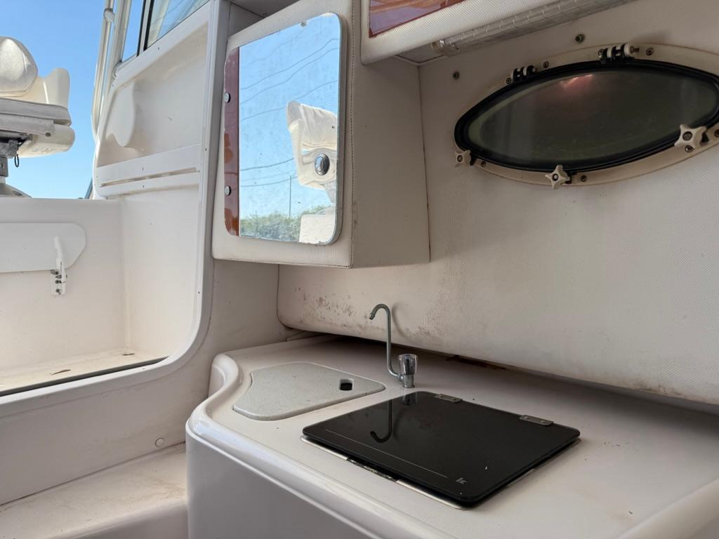 2000 Pro-Line 27 Walk boat interior with sink, mirror, and porthole window.