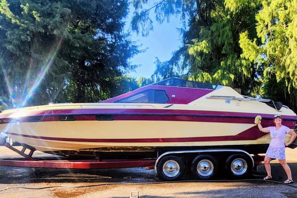 1980 Tahiti Ocean Racer boat on trailer, person cleaning, surrounded by trees.