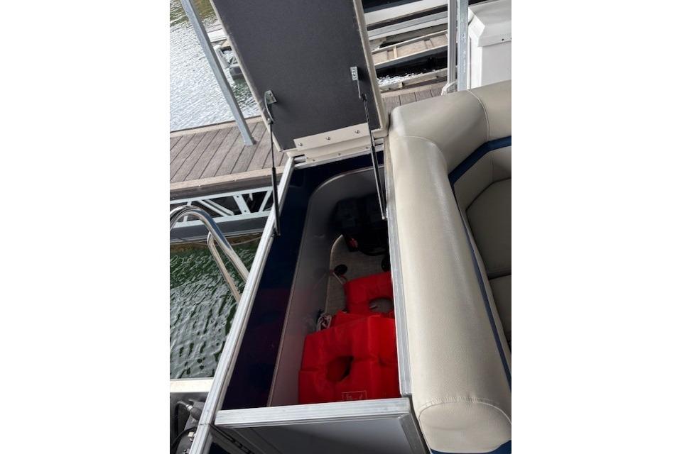 Open storage compartment on 2017 South Bay 222 RS boat with life jackets inside.